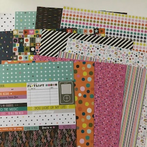 May include: A set of 16 patterned scrapbook paper sheets featuring musical notes, stars, polka dots, stripes, and smiley faces. The papers are in various colors, including black, white, pink, orange, yellow, green, and blue.