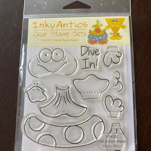 May include: Clear stamp set by Inky Antics, featuring a fish and duck maker theme. The set includes various clear stamps with cartoon-style designs, including a fish face, gloves, and the text "Dive In!"