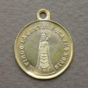 Peut inclure: Un pendentif en métal doré avec une représentation de la Vierge Marie et le texte "SS VIRGO LAURETANA ORA PRO NOBIS".