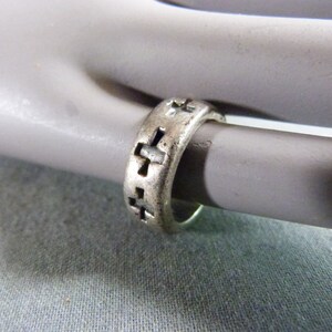 Peut inclure: Bague en argent avec un motif de croix. La bague est en métal et a une surface texturée.