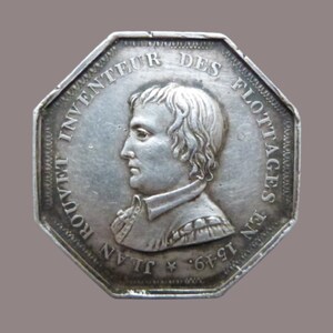 Puede incluir: Una medalla octogonal de plata con un retrato de un hombre y el texto "INVENTEUR DES FLOTTAGES EN 1749 JEAN ROUVET" alrededor del borde.