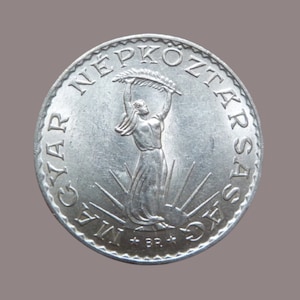 May include: A silver coin with the inscription "MAGYAR NÉPKÖZTÁRSASÁG" and a depiction of a woman holding a branch of leaves.
