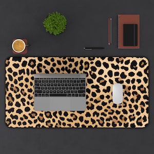 May include: A leopard print desk mat with a laptop, mouse, and coffee cup on top of it. The desk mat is a great way to add a touch of style to your workspace.