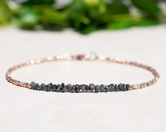 May include: A delicate bracelet made with a row of black diamonds and rose gold beads.