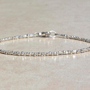 Puede incluir: Un delicado brazalete de plata hecho de peque&ntilde;as cuentas texturizadas. El brazalete tiene un cierre simple.