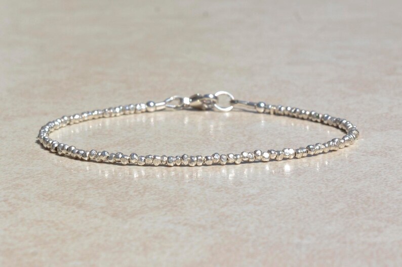 Puede incluir: Un delicado brazalete de plata hecho de peque&ntilde;as cuentas texturizadas. El brazalete tiene un cierre simple.