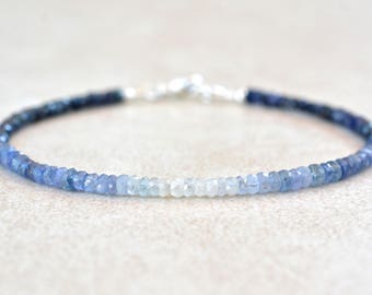 Puede incluir: Un delicado brazalete hecho con cuentas de piedras preciosas azules graduadas. Las cuentas varían en color de azul oscuro a azul claro, creando un efecto degradado. El brazalete está hecho con un cierre plateado.