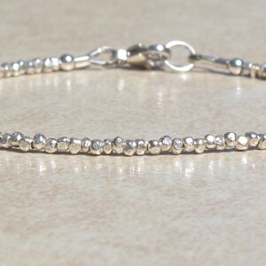 Puede incluir: Un brazalete de plata hecho de peque&ntilde;as cuentas texturizadas. El brazalete tiene un cierre simple.