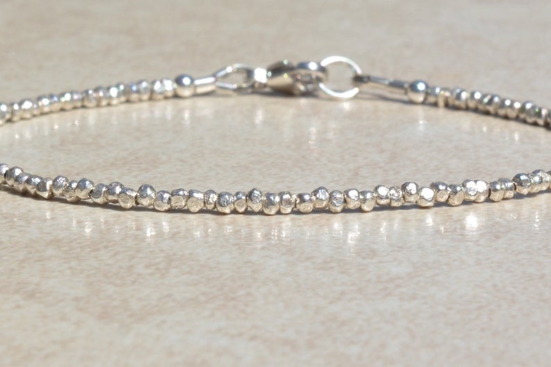 Puede incluir: Un brazalete de plata hecho de peque&ntilde;as cuentas texturizadas. El brazalete tiene un cierre simple.