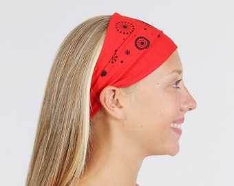 Könnte beinhalten: Ein rotes Stirnband mit einem schwarz-weißen geometrischen Muster. Das Stirnband wird von einer Person mit langen blonden Haaren getragen.