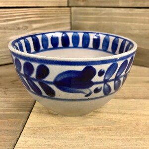 May include: A white ceramic bowl with a blue and white floral design. The bowl has a wide rim and a rounded bottom.