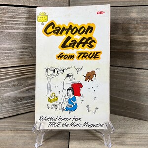 May include: A vintage paperback book titled "Cartoon Laffs from TRUE" with a cartoon illustration of a couple picnicking in a field with a bull. The book cover is white with red and black text and a red and gold crest logo. The book is 25 cents.