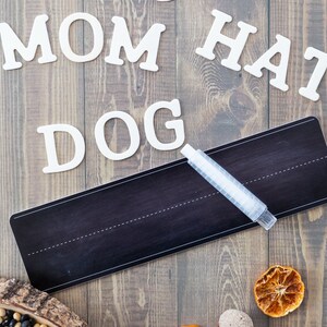 Peut inclure: Lettres en bois blanc &eacute;pellant les mots "RUN CAR MOM HAT DOG" sur une surface en bois brun. Un tableau noir avec un marqueur blanc est pos&eacute; sur la surface. On trouve &eacute;galement des tranches d'orange s&eacute;ch&eacute;es et des glands sur la surface.