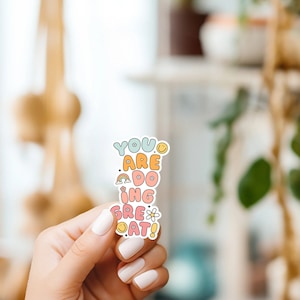 May include: A sticker with a colourful design that says "You are doing great!" with a rainbow and a flower.