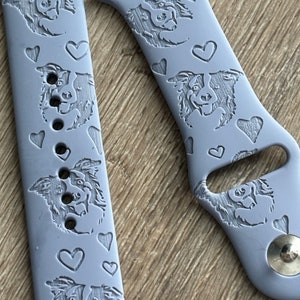 May include: A pair of light gray silicone Apple Watch bands with a repeating pattern of a border collie dog and hearts. The bands are designed for a 42mm or 44mm Apple Watch.