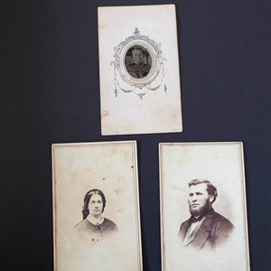 May include: Three vintage photographs, two portraits and one with a decorative oval frame. The portraits are of a woman and a man, both in black and white. The woman is wearing a dark dress and a white collar. The man is wearing a dark suit and a white shirt with a dark tie. The oval frame is ornate and has a floral design.