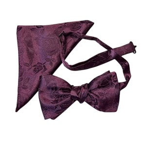 May include: A formal set in a deep burgundy color, featuring a bow tie and a matching pocket square. Both items have a subtle floral pattern, perfect for special occasions.
