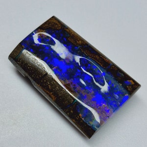 May include: A blue and white opal cabochon with a brown ironstone matrix. The opal has a bright blue and white play of colour.