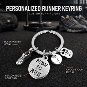 Puede incluir: Un llavero de metal plateado con tres dijes: una zapatilla de correr, un disco redondo grabado con el texto BORN TO RUN, un disco más pequeño con la letra J y un dije en forma de pesa rusa con el texto WOD & FIT grabado en la superficie.
