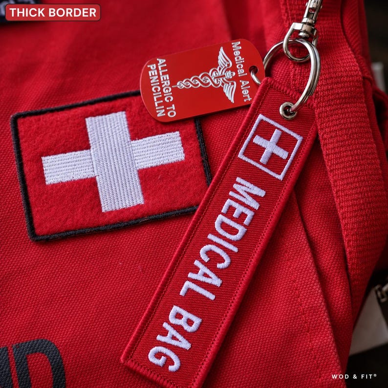 May include: A red medical bag featuring a white cross patch and a red fabric keychain embroidered with white text reading MEDICAL BAG. A red metal medical alert tag with a white caduceus symbol and the text ALLERGIC TO PENICILLIN is attached.