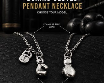 May include: Two silver-toned metal boxing glove pendant necklaces with stainless steel chains. One pendant includes a small charm embossed with the text WOD & FIT. The jewelry features a metallic finish and is displayed against a dark background.
