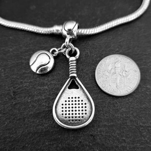 May include: Silver charm bracelet with a silver tennis racket and ball charm. The charm is attached to a silver chain.
