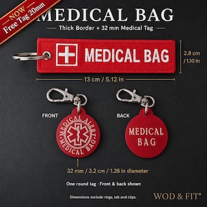 Op de afbeelding: Een rechthoekige rode geborduurde sleutelhanger met een wit kruis en de tekst MEDICAL BAG, van 13 cm bij 2,8 cm. Inclusief een ronde rode tag met een diameter van 3,2 cm met een medisch waarschuwingssymbool op de voorzijde en tekst op de achterzijde.