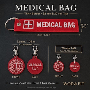 Könnte beinhalten: Ein roter, rechteckiger Schlüsselanhänger aus Stoff mit weißem medizinischem Kreuz und der Aufschrift MEDICAL BAG sowie zwei runde Anhänger in 32 mm und 20 mm. Jeder runde Anhänger zeigt ein medizinisches Symbol vorne und MEDICAL BAG hinten.