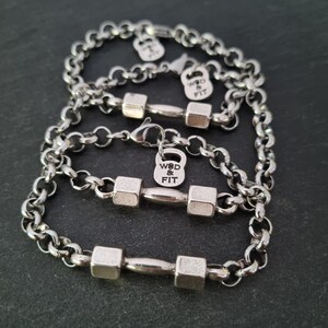 May include: Three silver chain bracelets with dumbbell charms. Each charm has the text "WOD & FIT" engraved on it.