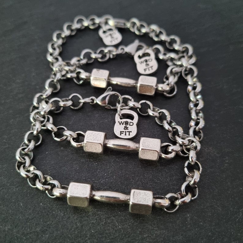 May include: Three silver chain bracelets with dumbbell charms. Each charm has the text "WOD & FIT" engraved on it.