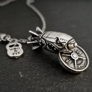 Collana con ciondolo a forma di gomma in acciaio inox e gomma occhielli, in un sacchetto di velluto nero