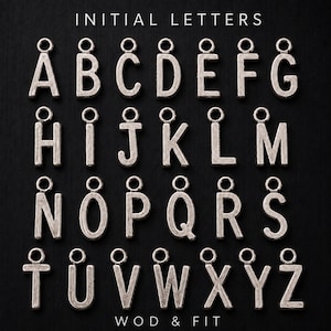 Puede incluir: Una colección de dijes de letras del alfabeto en metal plateado, cada uno con un pequeño lazo circular en la parte superior para su fijación. Las letras de la A a la Z están dispuestas en cuatro filas, con el texto INITIAL LETTERS y WOD & FIT.