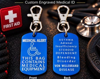 Puede incluir: Dos etiquetas rectangulares de metal azul con cierres de mosquetón plateados. La etiqueta frontal muestra un icono de silla de ruedas blanco y el texto MEDICAL ALERT THIS BAG CONTAINS MEDICAL EQUIPMENT. La etiqueta trasera enumera condiciones.