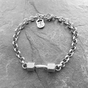 May include: A silver chain bracelet with a dumbbell charm and a small tag that says "WOD & FIT".