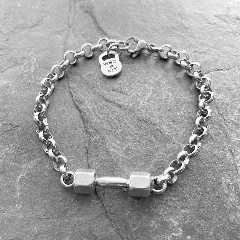 May include: A silver chain bracelet with a dumbbell charm and a small tag that says "WOD & FIT".