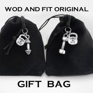 May include: Two black velvet drawstring bags with silver charms. Each charm features a dumbbell and a small silver tag that says "WOD & FIT".