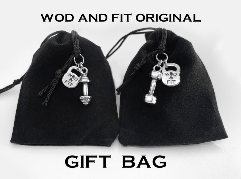 May include: Two black velvet drawstring bags with silver charms. Each charm features a dumbbell and a small silver tag that says "WOD & FIT".