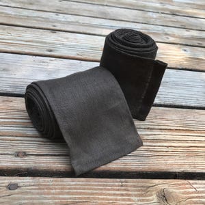 May include: Two rolls of dark brown linen fabric. The fabric is rolled up and tied with a simple knot.