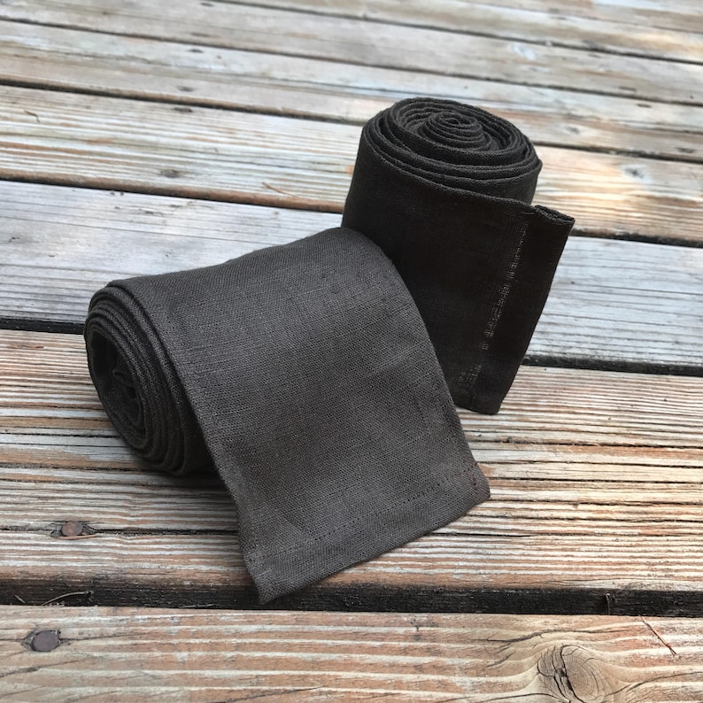 May include: Two rolls of dark brown linen fabric. The fabric is rolled up and tied with a simple knot.