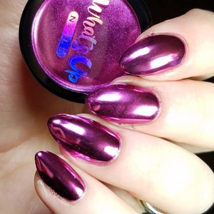 K&ouml;nnte beinhalten: Nahaufnahme von Fingern&auml;geln mit einem leuchtend pinken Chrom-Nagellack. Die N&auml;gel sind lang und oval geformt. Das Bild zeigt auch ein kleines Glas Nagellack mit dem Text "What's Up Nails" auf dem Etikett.