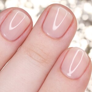May include: Close-up of three fingernails with a light pink nail polish. The nails are smooth and shiny.
