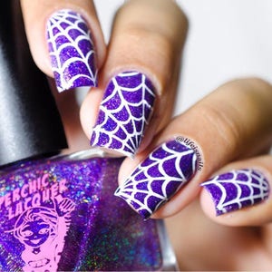 May include: Purple nail polish with a white spiderweb design. The nail polish bottle is labeled "Perchic Lacquer".