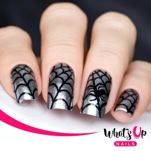 May include: Close-up of four fingernails with a silver and black spiderweb design. The design features a black spider on one nail. The nails are painted with a silver glitter polish.