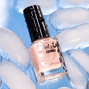 May include: A clear glass bottle of light pink nail polish with a black cap. The bottle is surrounded by ice cubes and the label reads "What's Up Nails" with a 0.37 fl oz volume.