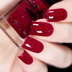 Könnte beinhalten: Nahaufnahme von vier Fingernägeln, die mit einem tiefroten Nagellack mit feinem Glitzerfinish lackiert sind.