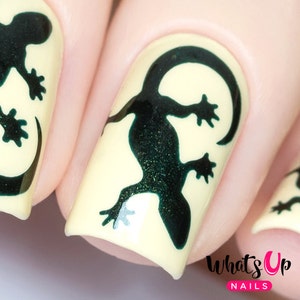 May include: Close-up of a fingernail with a black gecko silhouette design on a yellow background. The nail is surrounded by other nails with similar designs.