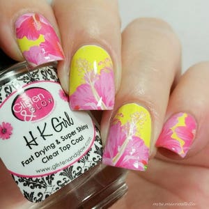Puede incluir: Primer plano de una mano con esmalte de u&ntilde;as rosa y amarillo con un dise&ntilde;o floral. El esmalte de u&ntilde;as est&aacute; etiquetado como "HK Girl Fast Drying & Super Shiny Clear Top Coat" y "Glisten & Glow".