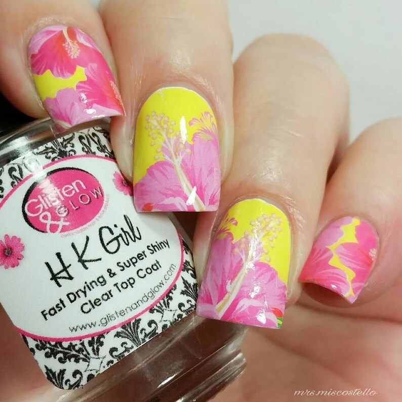 Puede incluir: Primer plano de una mano con esmalte de u&ntilde;as rosa y amarillo con un dise&ntilde;o floral. El esmalte de u&ntilde;as est&aacute; etiquetado como "HK Girl Fast Drying & Super Shiny Clear Top Coat" y "Glisten & Glow".