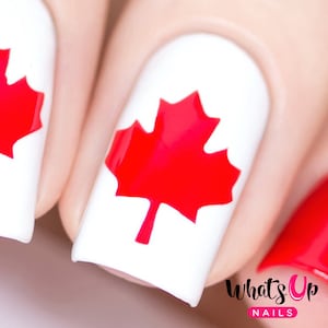 May include: Close-up of a white nail with a red maple leaf design. The nail is part of a set of nails with a Canadian flag theme. The text "What's Up Nails" is visible in the bottom right corner of the image.