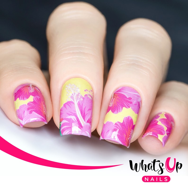 Puede incluir: Primer plano de cinco u&ntilde;as con un dise&ntilde;o de arte de u&ntilde;as floral amarillo y rosa. El dise&ntilde;o presenta flores de hibisco rosas sobre un fondo amarillo. El arte de u&ntilde;as est&aacute; etiquetado como "What's Up Nails".